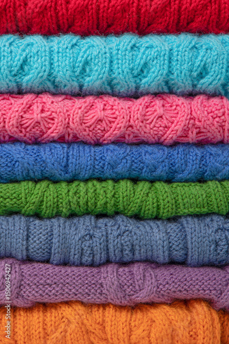 Abstract knitted background from set of multicolored knitted clothes stacked. Space for text. Knitting warm clothes, blankets and blankets. Concept of home needlework