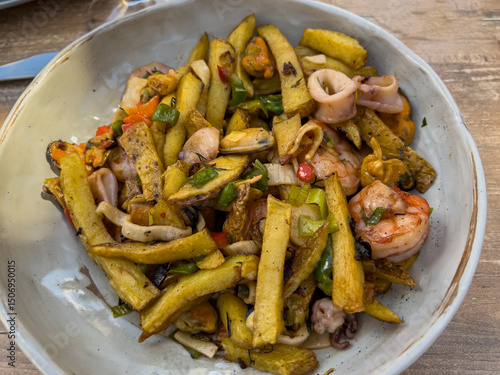 Traditional food from Mallorca: fried potatoes with seafood and green onions, top view