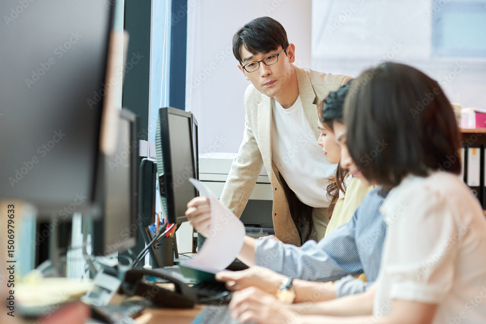 Fototapeta premium Young Asian Man and Woman Working Together in Modern Office with Computers and Telephone