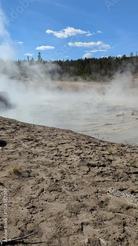 Yellowstone Mud Volcano Trail shows steaming mud pot and blue sky