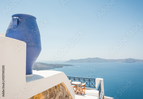 Fototapeta Naklejka Na Ścianę i Meble -  Blue vase, table with two chairs on the cliff of Santorini island. Terrace with a view from Thera village at Cyclades islands.