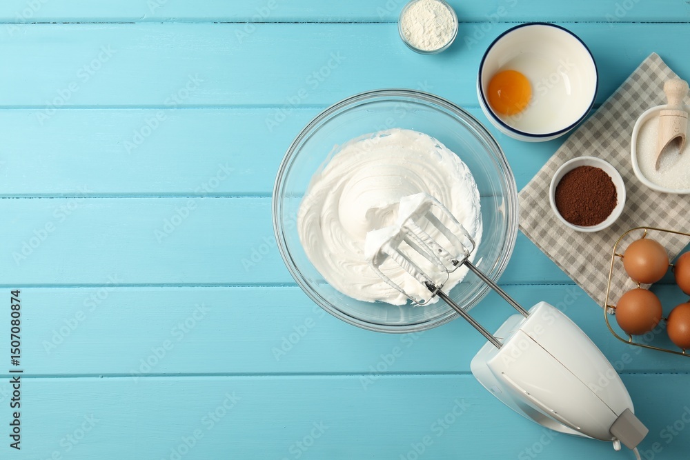 Fototapeta premium Bowl with whipped cream, hand mixer and ingredients on light blue wooden table, flat lay