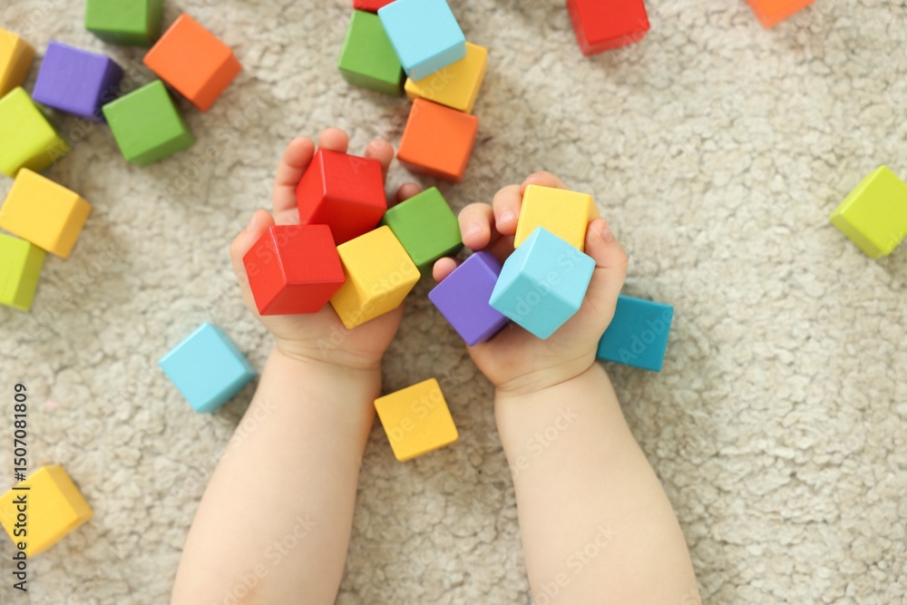 Naklejka premium Cute little child playing with colorful cubes at home, above view