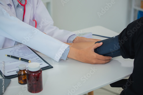 Female doctor gives advice and explains to patient for annual health check in examination room by measuring blood pressure and taking basic history. Health care and medicine concept.