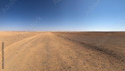 Panoramic photograph of a long, empty desert road in the Sahara Desert with a clear blue sky