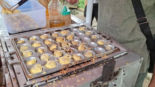 Fried pentol is one of the street foods that is usually served with chili sauce or tomato sauce. A man's hand is seen busy frying pentol in its place.