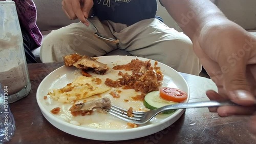 A boy enjoys some fried chicken left over. Vegetables while eating.