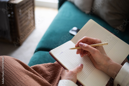 girl woman writes word goal in diary. concept of goal setting, planning, self-improvement and personal growth. home domestic life in cozy house