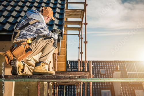 Φωτογραφία Construction Worker Inspecting Tools While Kneeling on Scaffolding at a Building