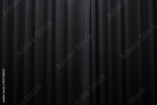 Close-up view of a black pleated curtain with subtle lighting