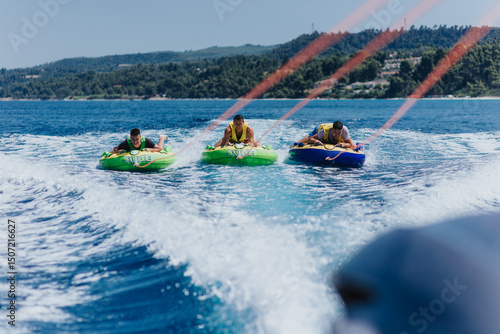 Valokuva Group of friends having fun tubing behind a speedboat on a sunny day, enjoying an adventurous and thrilling water activity