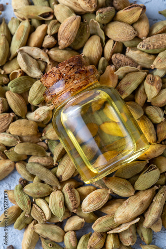 Green cardamom essential oil and cardamom pods in glass containers