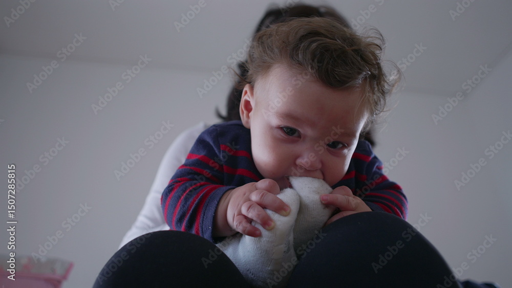 Baby playing with sock, holding and biting while sitting on mother’s lap, curious and playful interaction in home environment, exploring textures with curiosity Baby playing with sock, holding and biting while sitting on mother’s lap, curious and playful interaction in home environment, exploring textures with curiosity