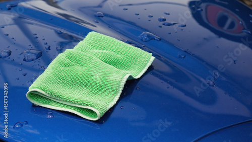 Shining Surface: A close-up shot of a vibrant blue car surface being meticulously cleaned with a soft, green microfiber cloth. The glossy finish reflects the light.