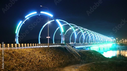 Night illumination of modern automobile bridge with multi-colored arches