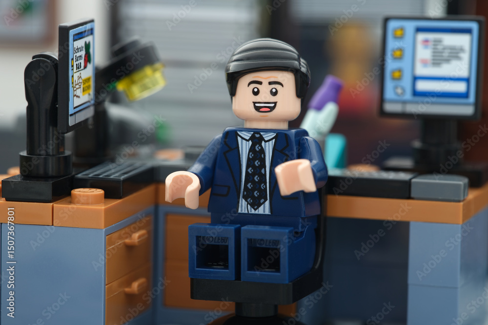 Obraz premium Tambov, Russian Federation - May 26, 2025 A happy Lego businessman minifigure sitting on a chair behind a computer in an office and looking at the camera. Close up.