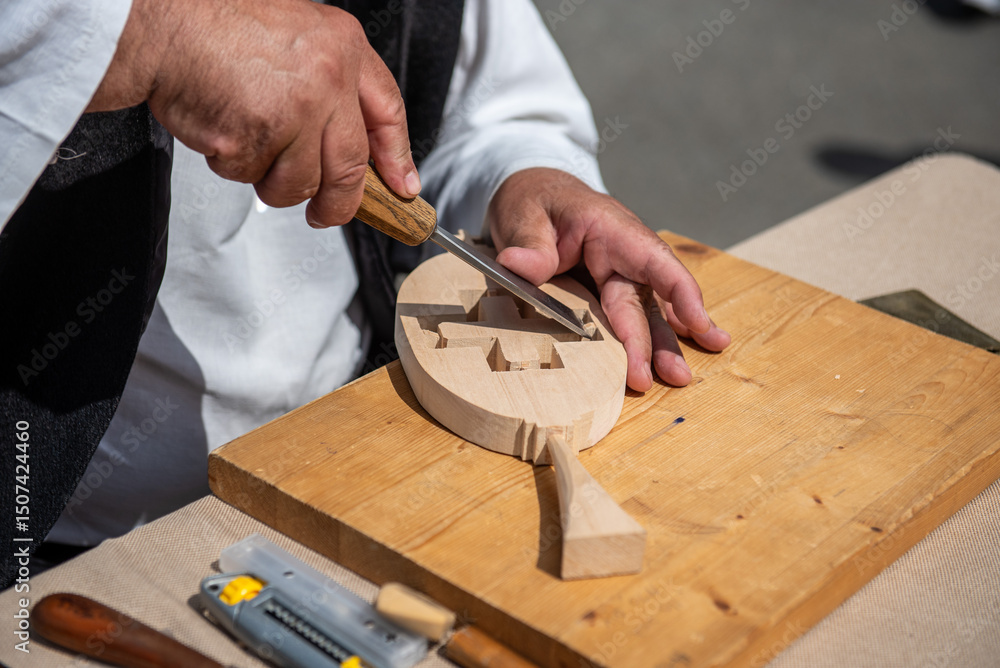 Woodcarvers hands carving decorative patterns on wood with traditional tools