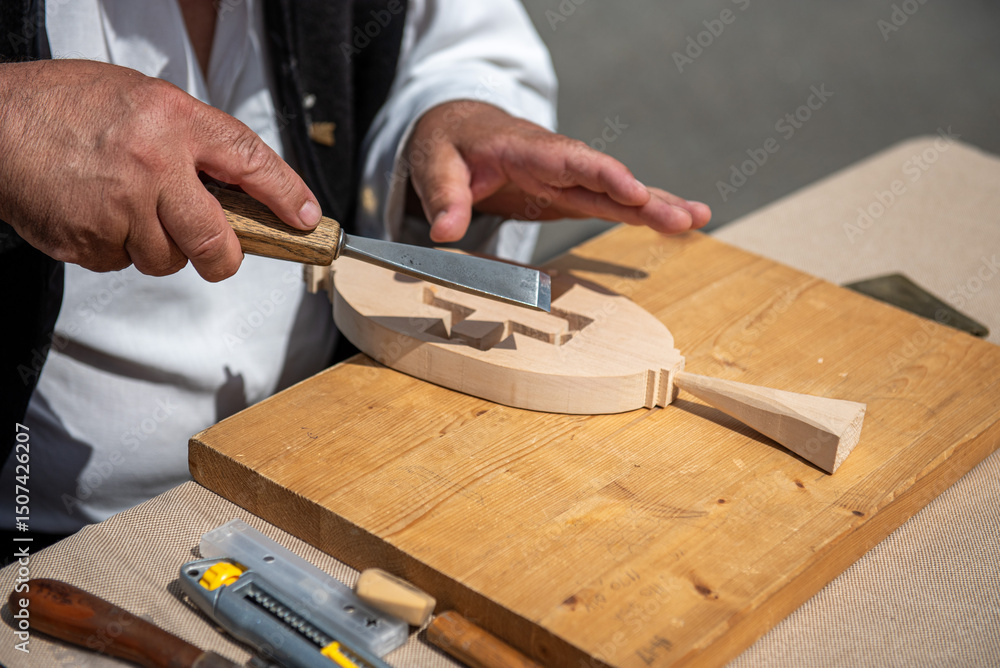 Woodcarvers hands carving decorative patterns on wood with traditional tools