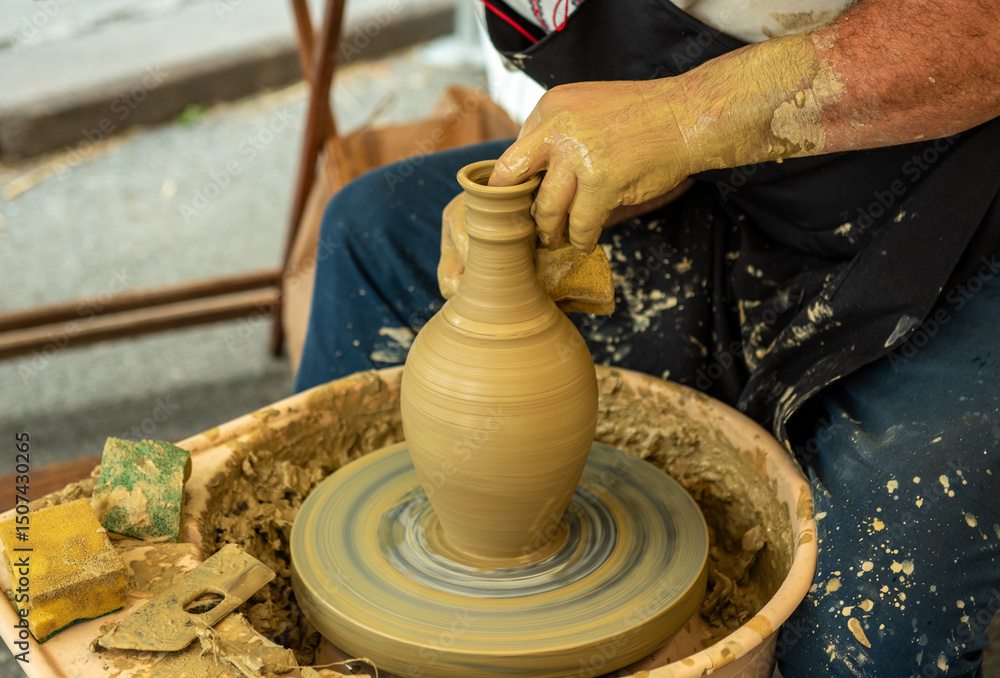 Potters hands shaping a clay jug on a pottery wheel at a traditional craft festival