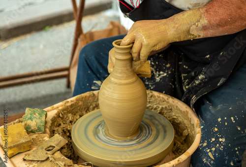 Potters hands shaping a clay jug on a pottery wheel at a traditional craft festival