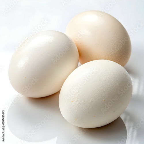 Three smooth, fresh organic eggs with natural brown shells rest neatly on a pristine white surface