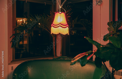 view of a hanging lamp over a sofa providing an orange warm light in a dark and moody room