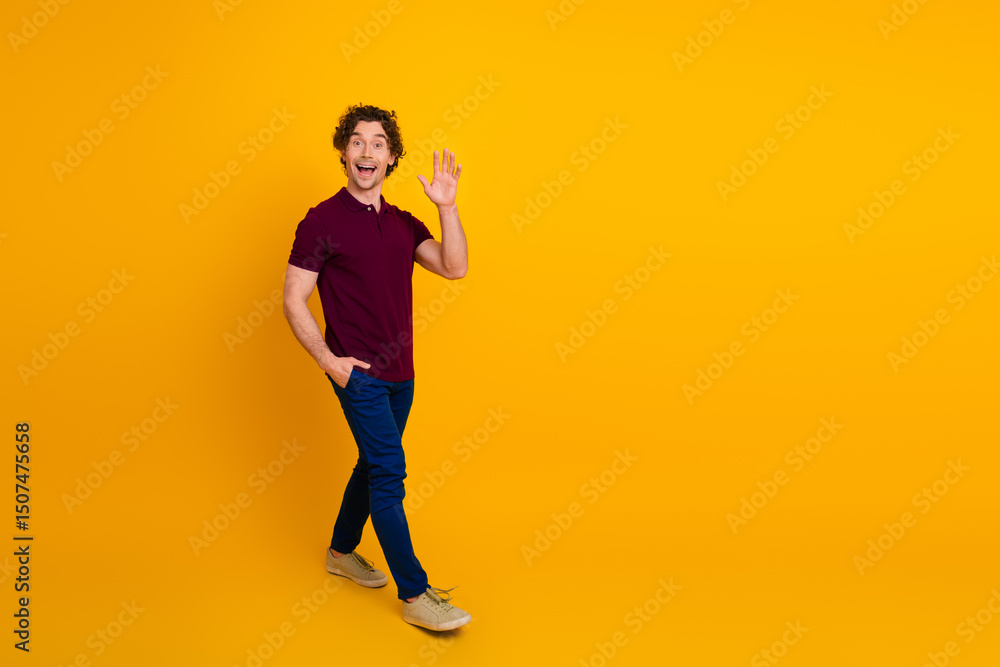 Young man in a casual outfit gesturing a friendly wave with an enthusiastic expression standing against a yellow background. Young man in a casual outfit gesturing a friendly wave with an enthusiastic expression standing against a yellow background.