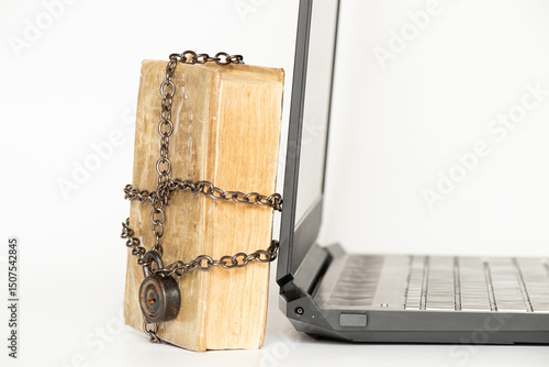 Old book in chains next to modern laptop on white background