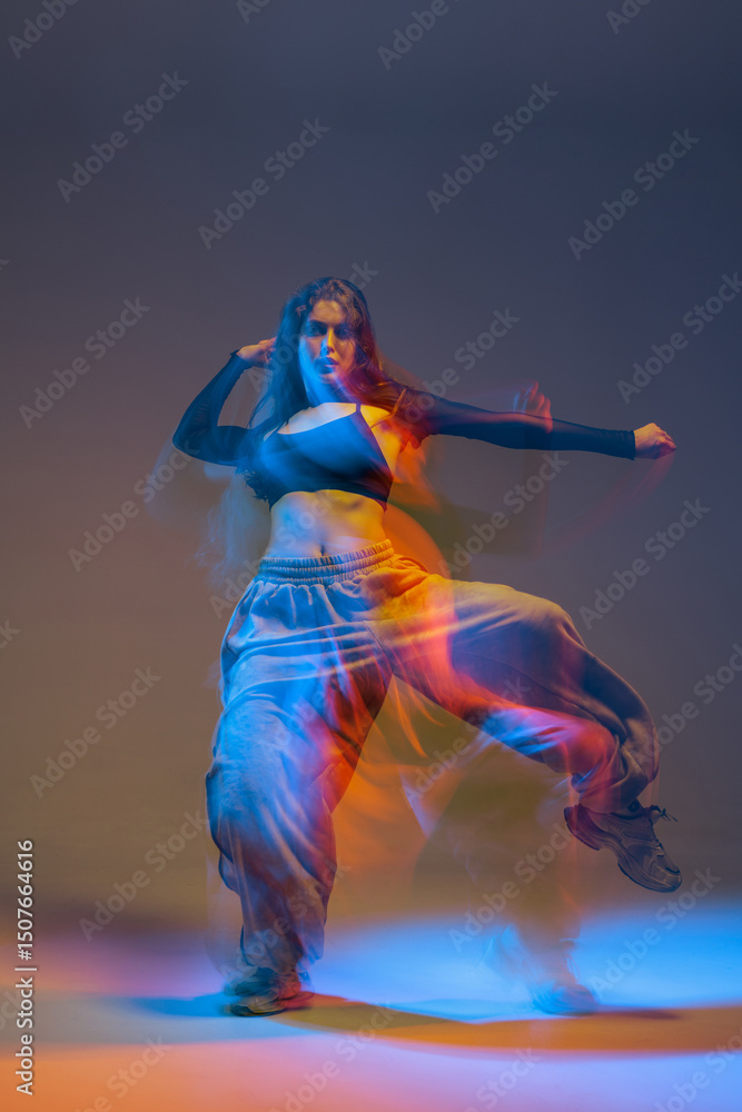 Obraz premium Energetic female jazz-funk dancer in motion blur with glowing neon lights, showing strength, rhythm, and bold urban attitude in a vibrant, stylized studio environment.