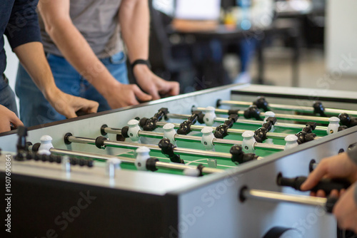 Group playing foosball in office break area