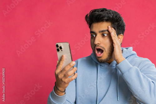 Obraz na plátně Upset sad Indian man use smartphone typing browsing, play game, loses, surprised by sudden lottery results bad fortune loss fail unlucky news