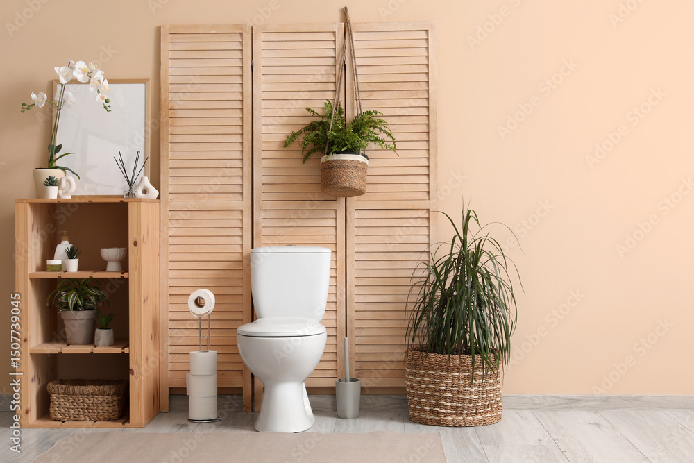 Fototapeta premium Modern interior of restroom with ceramic toilet bowl, shelving unit and plants