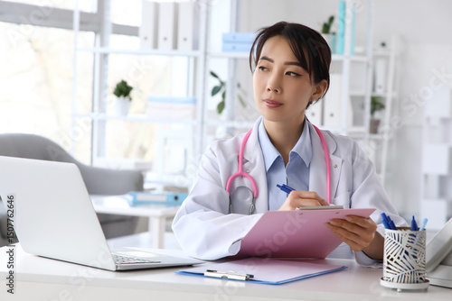 Female Asian doctor writing...