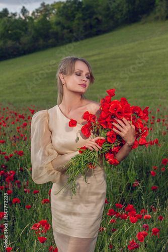 Attractive young woman in a beige dress sitting in a blooming poppy field on a sunny day. Concept of femininity, serenity, connection with nature, rural elegance, seasonal flowers and summer vibes.