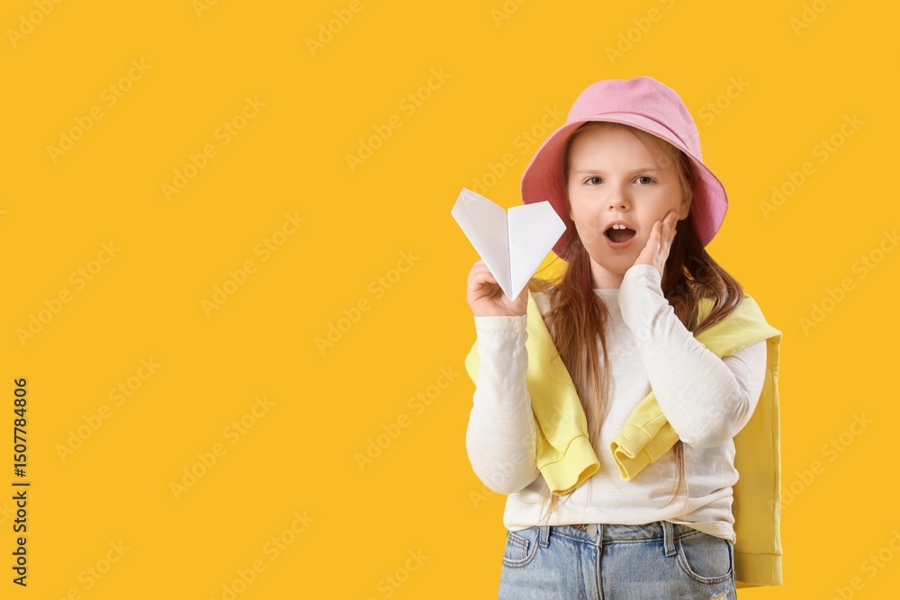 Surprised girl with paper plane on yellow background Surprised girl with paper plane on yellow background