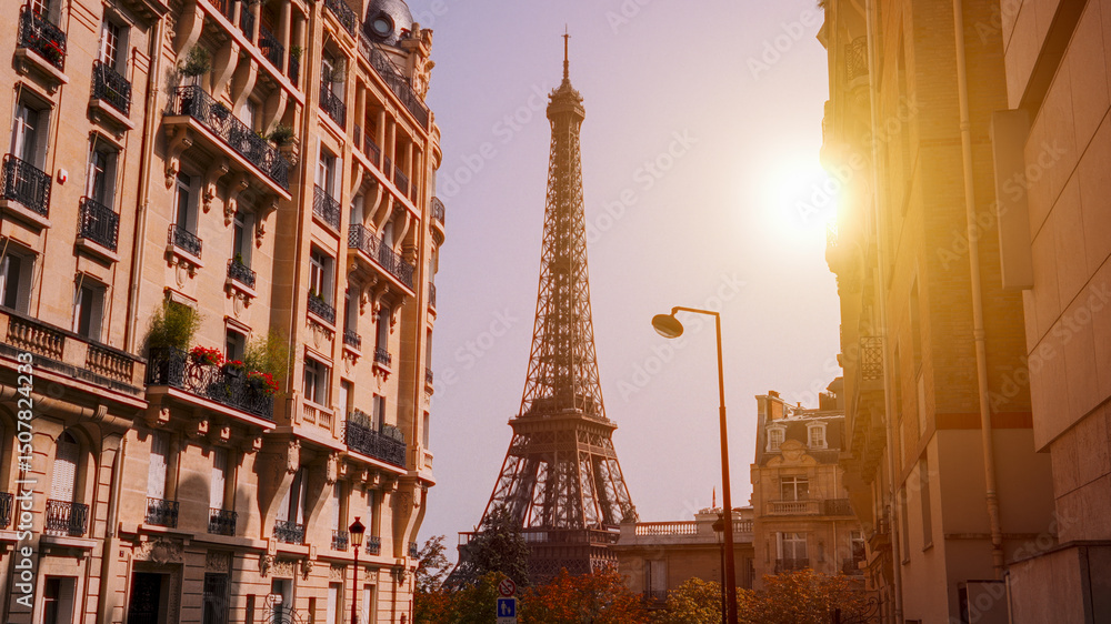Obraz premium Sun shining over the Eiffel Tower framed by Parisian buildings at sunset