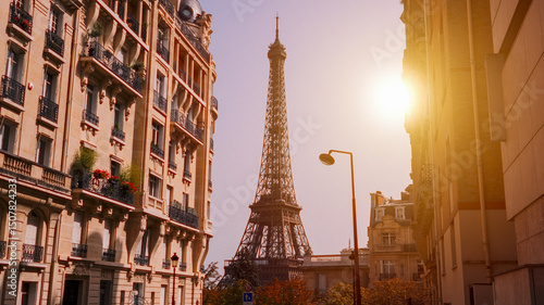 Fototapeta Naklejka Na Ścianę i Meble -  Sun shining over the Eiffel Tower framed by Parisian buildings at sunset