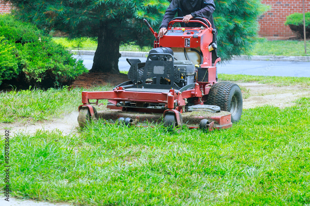 Obraz premium Riding lawn mower is efficiently trimming grass in well maintained residential garden