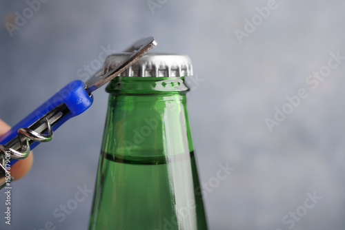 Quadro su tela Opening a green glass bottle with a bottle opener