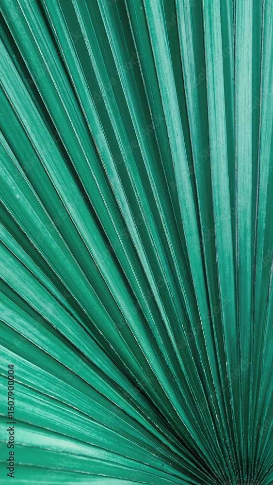 Obraz premium A vibrant green palm leaf showcasing intricate textures and patterns, with smaller leaves nestled within its lush, tropical foliage, creating a serene atmosphere.