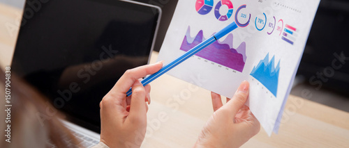 Closeup two businesswoman reviewing financial graphs and charts in modern office, two business woman meeting analyzing and planning statistics finance of marketing, business and investment.