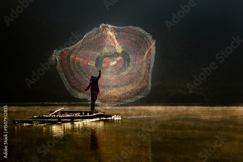 A fisherman throwing a fishing net on lake Situ Gunung. Situ Gunung is beautiful lake surrounded by thick forest on the foot of mount Gede Pangrango.