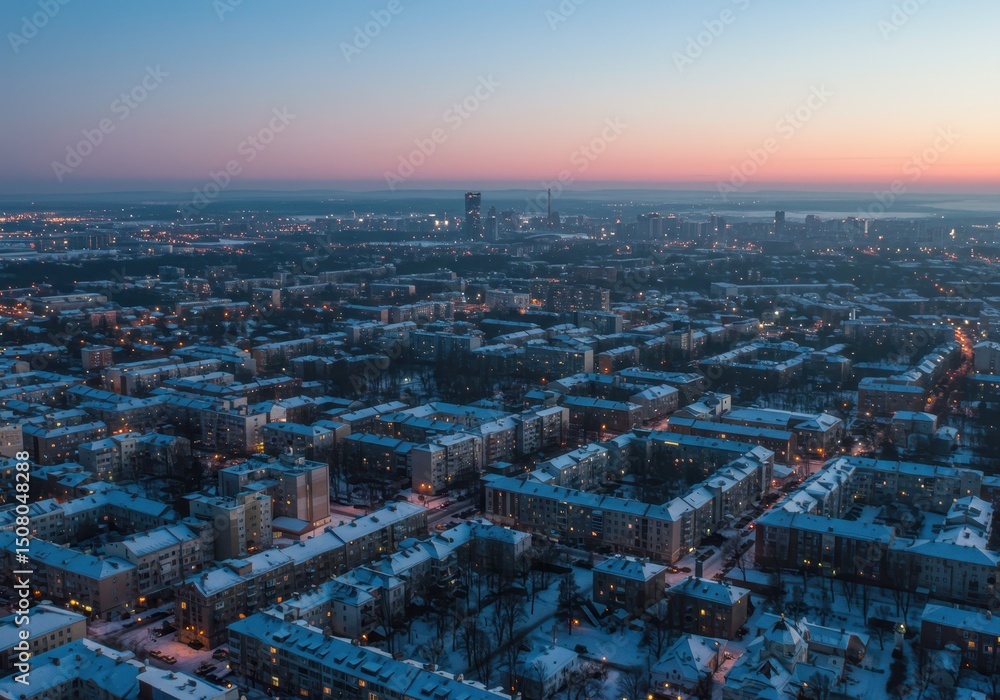Obraz premium Snow covered city buildings and streets at dusk from an aerial view