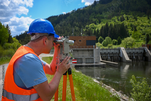 Fotografi Surveyor working with theodolite near hydroelectric power plant and dam