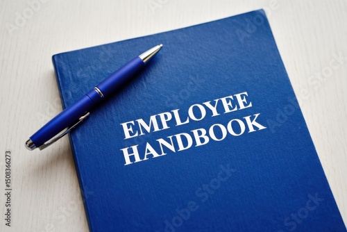 Employee handbook placed on a wooden surface with a blue pen nearby, symbolizing workplace guidance and policies