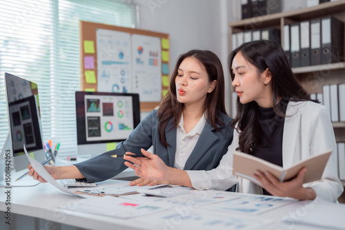 Photography Two young businesswomen are examining financial charts and discussing data in a