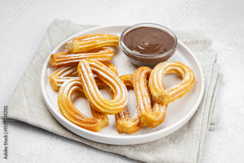 Traditional spanish dessert churros, fried dough pastry dusted with powdered sugar and chocolate sause macro, close up, on white background. Street food, sweet snack, homemade dessert