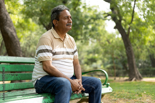 Depression, thinking, Upset lonely homeless senior man in garden sitting on bench with depression holds head in hands. Sad, worried indian mature male with thoughtful face expression