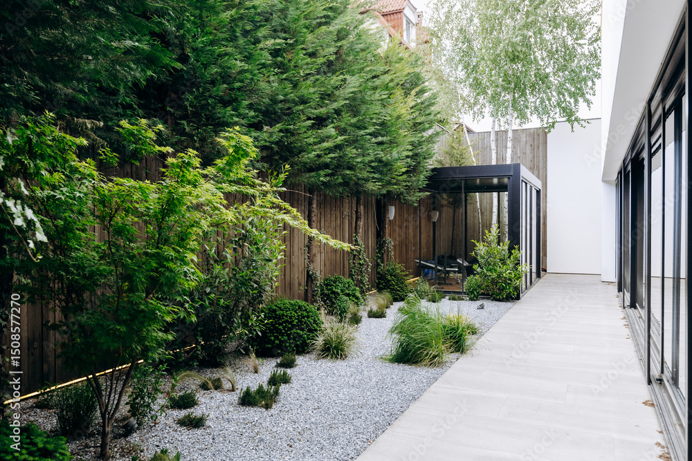 Fototapeta premium A beautiful walkway leads to a house amid lush trees and vibrant bushes