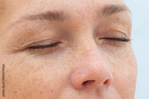 Woman face with closed eyes showing natural skin and wrinkles around the eyes